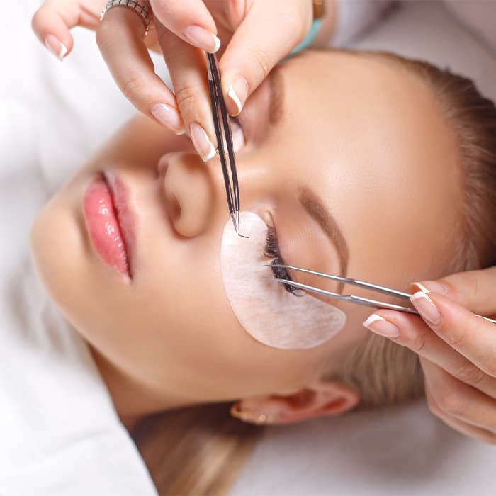 Kobieta w trakcie wykonywania usługi przedłużania rzęs