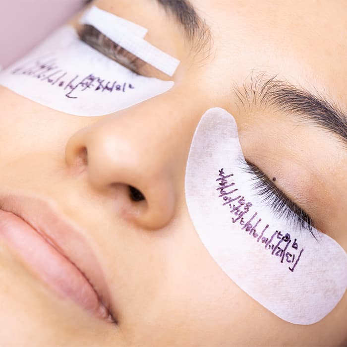 Kobieta w trakcie wykonywania usługi przedłużania rzęs