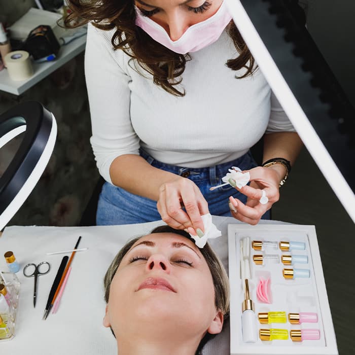 Specjalistka wykonuje zabieg przedłużenia rzęs oraz liftingu brwi 