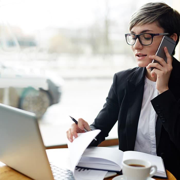 kobieta pracuje na laptopie i rozmawia przez telefon komórkowy 