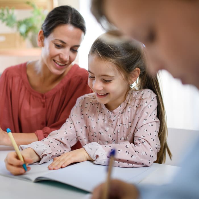asystent rodziny odrabia pracę domową z dzieckiem