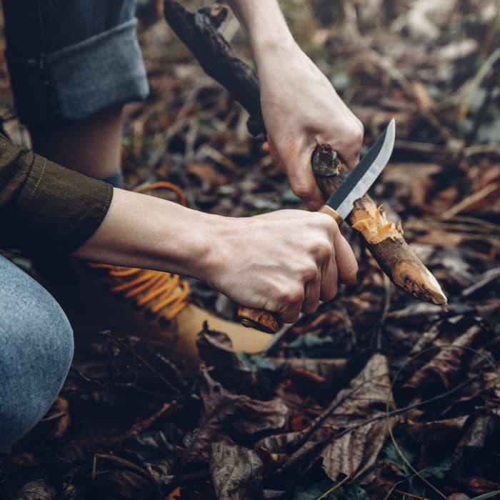 mężczyzna używa noża do strugania drewna