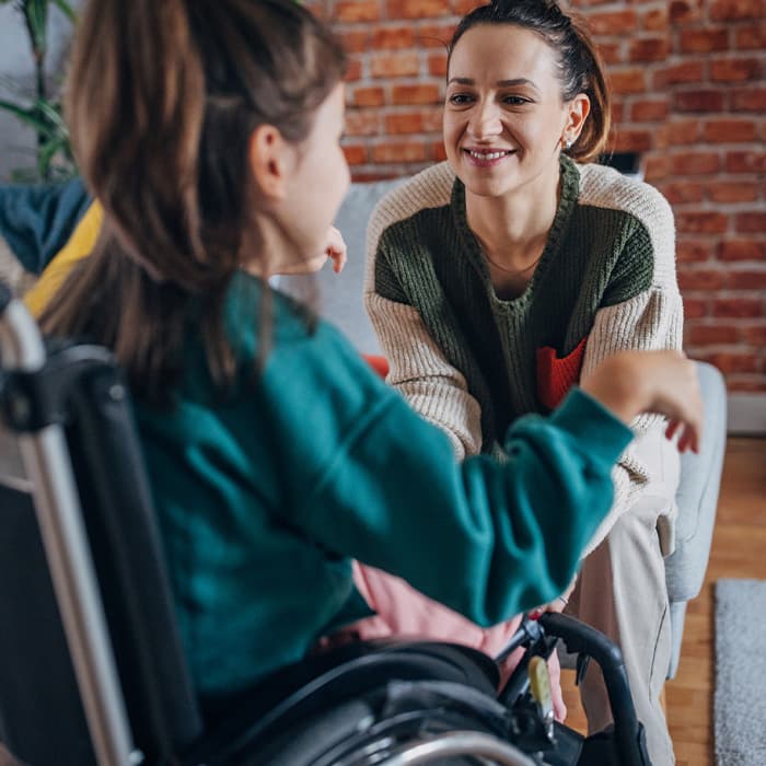 asystent opiekuje się dziewczynką na wózku inwalidzkim