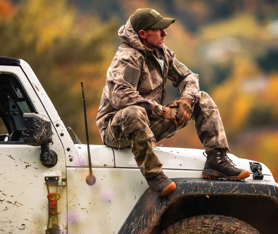 mężczyzna siedzi na masce samochodu terenowego